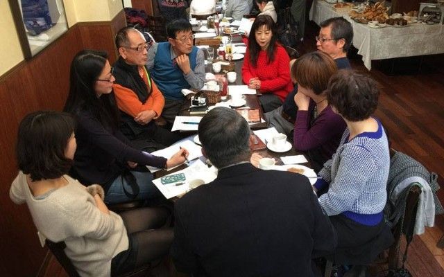 TJCS volunteers sitting around a table in a restaurant, engaged in conversation.