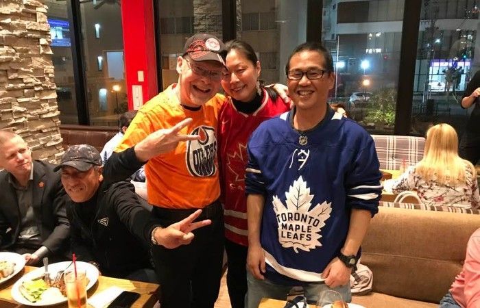 A group of people wearing NHL hockey sweaters  are posing for a picture in a restaurant.