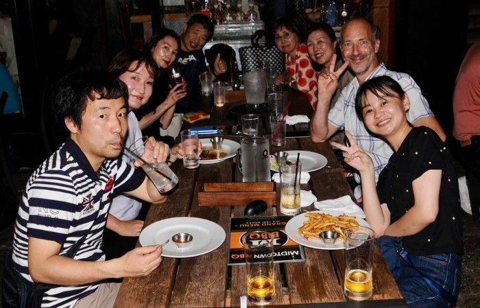 A group of people are sitting at a table with plates of food and drinks