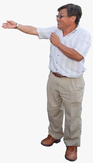 Man in light-colored shirt and pants gestures with one arm outstretched. He smiles.