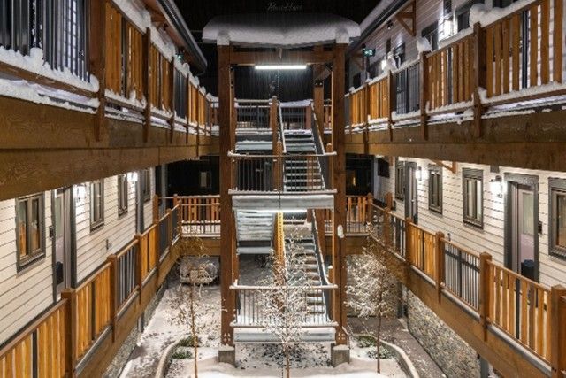 Multi-level wooden building exterior with snow, stairs, and walkways.
