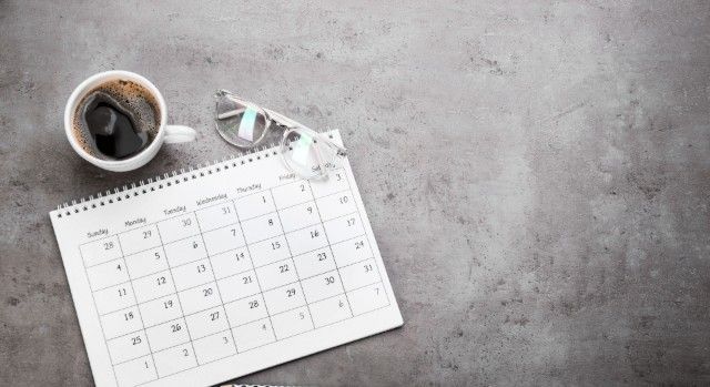 灰色の表面にカレンダー、眼鏡、コーヒーカップ。