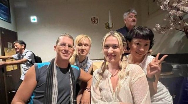 室内での集合写真：笑顔の人たち、ピースサインをする人たち。桜とバーの雰囲気。