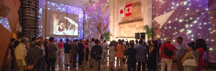 壁に投影された大きなホールで、人々が映画を鑑賞している。カナダ国旗が掲げられている。