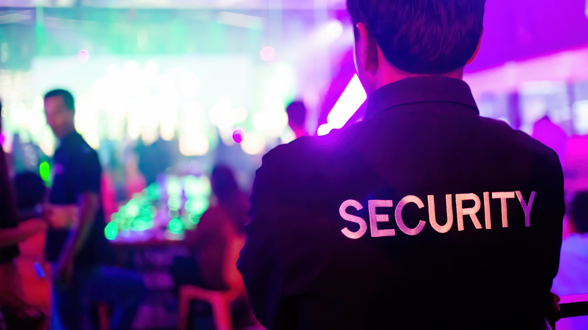 a security guard is standing in front of a crowd at a party .