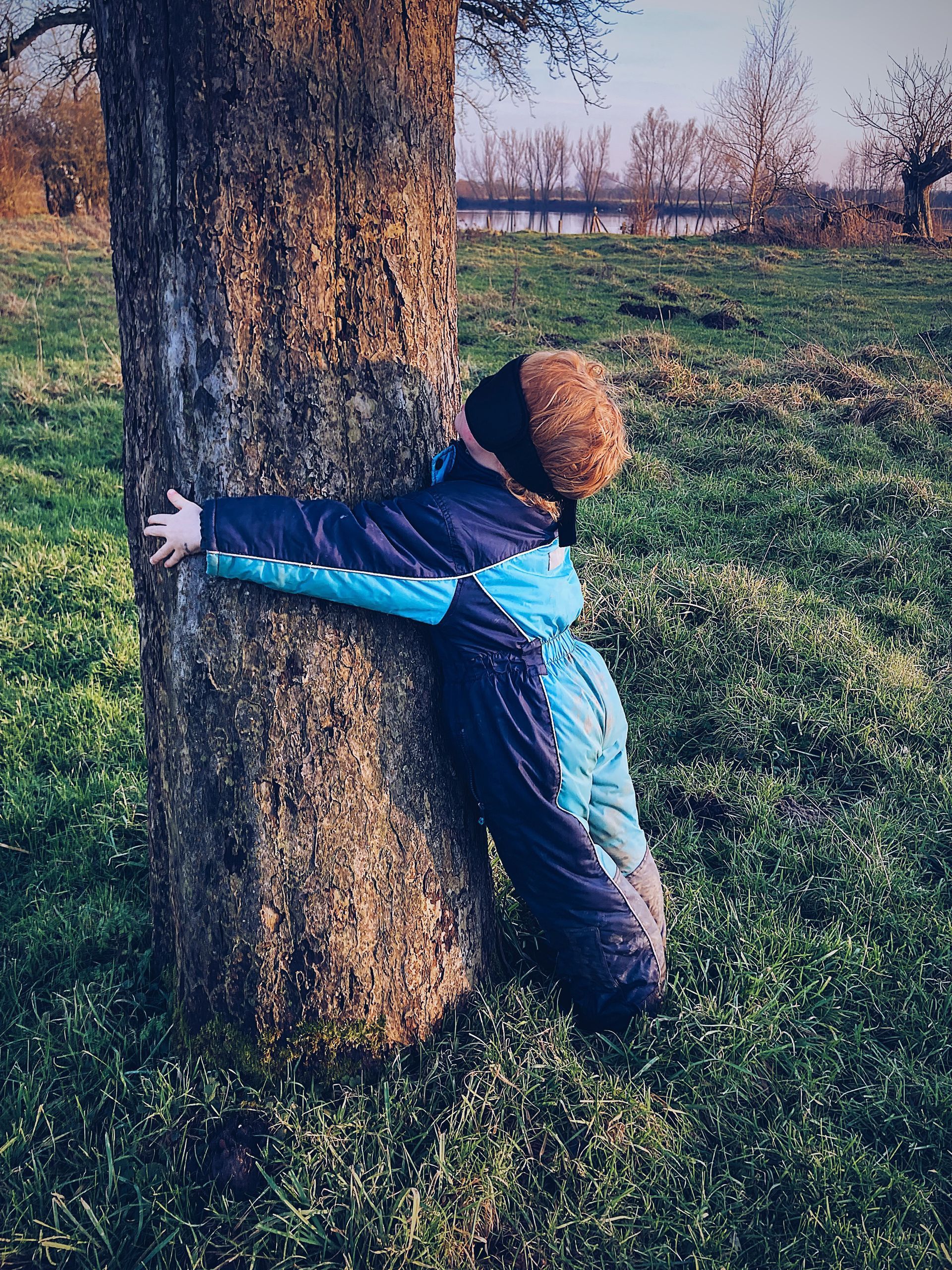 hoogsensitief Meisje knuffelt een boom met blinddoek – zintuiglijke natuurervaring bij Willow BSO in Lathum