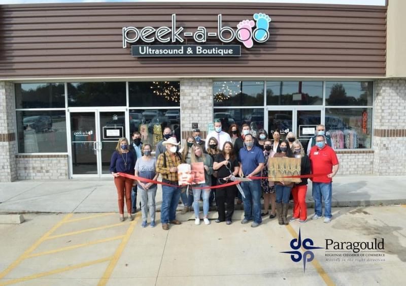 Group of people outside Peek-a-Boo Consignment & Boutique holding a ribbon across the storefront