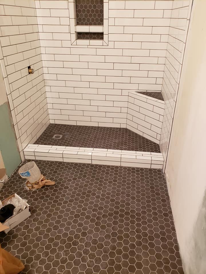 A bathroom with white brick walls and a black tile floor.