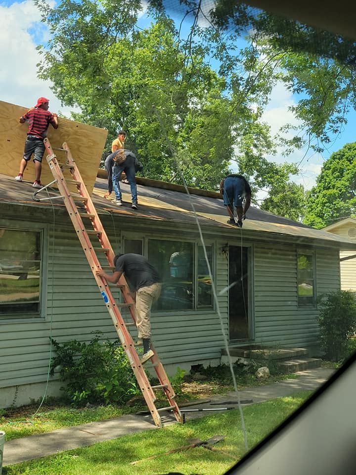 A group of people are working on the roof of a house.
