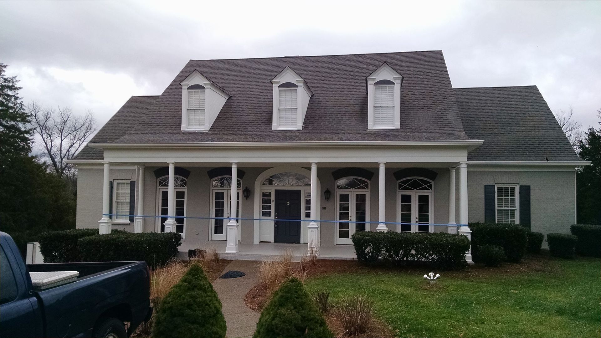 A large house with a blue truck parked in front of it