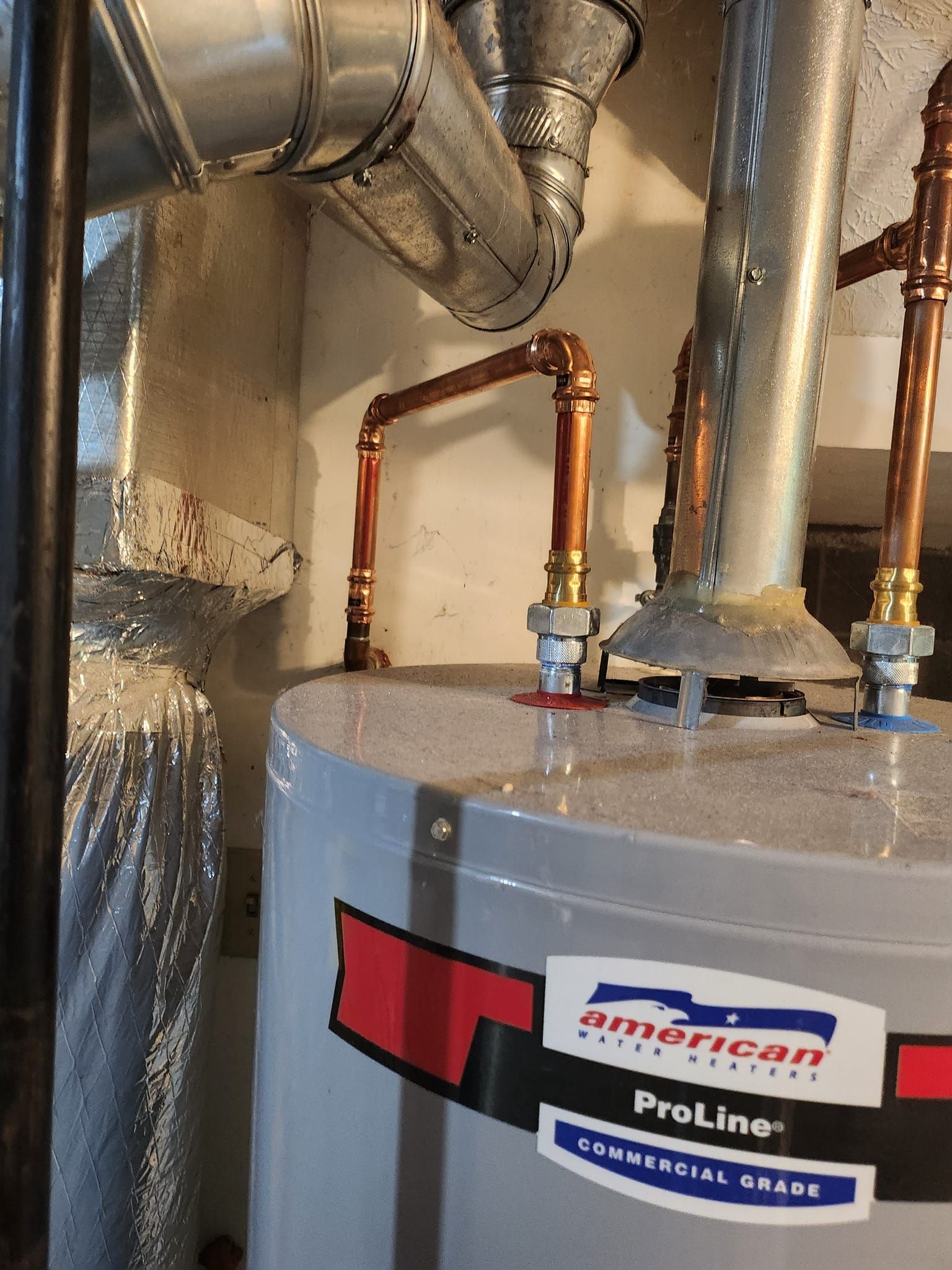 A water heater is sitting in a basement next to copper pipes.