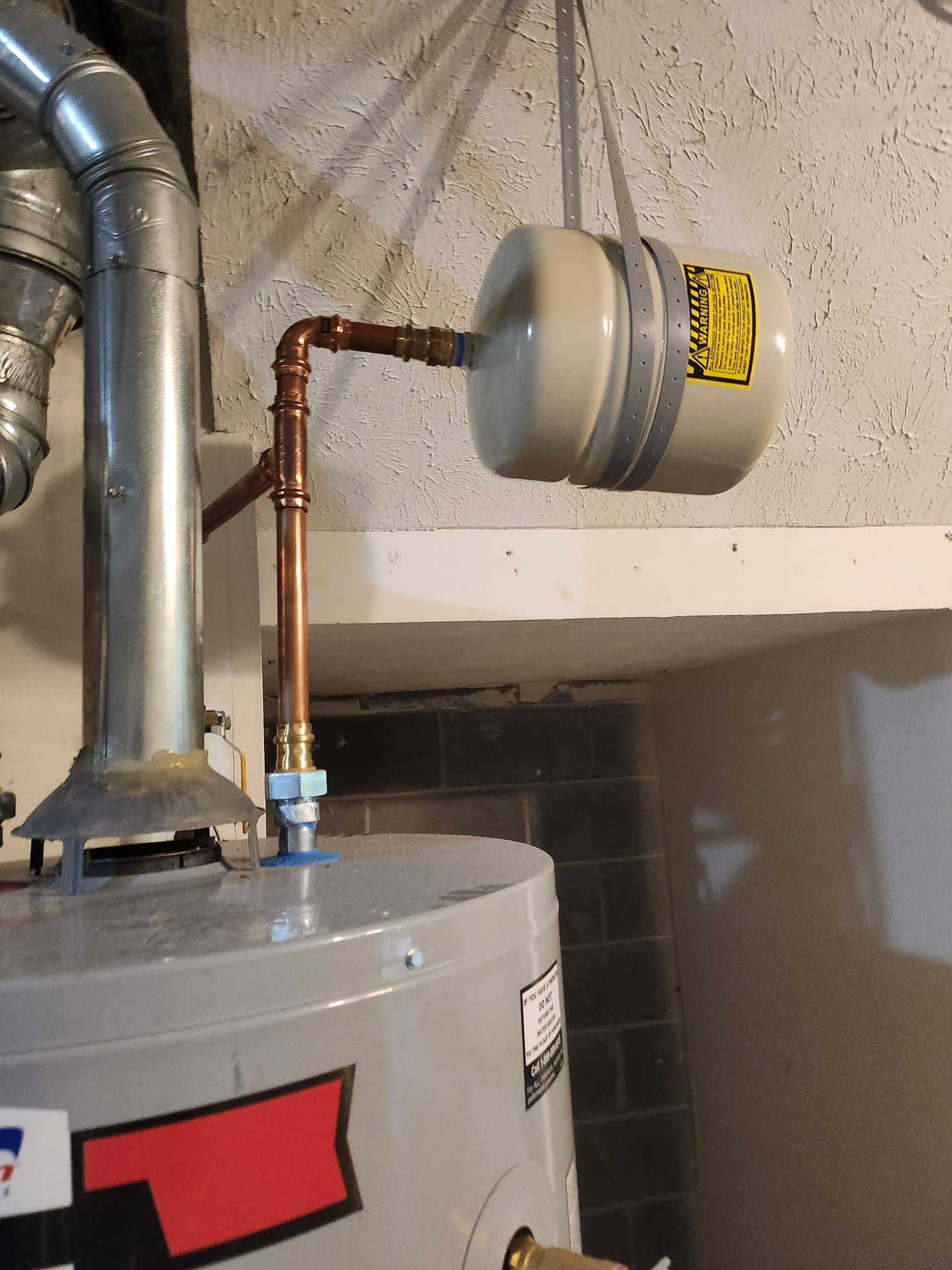 A water heater is hanging from the ceiling in a basement.