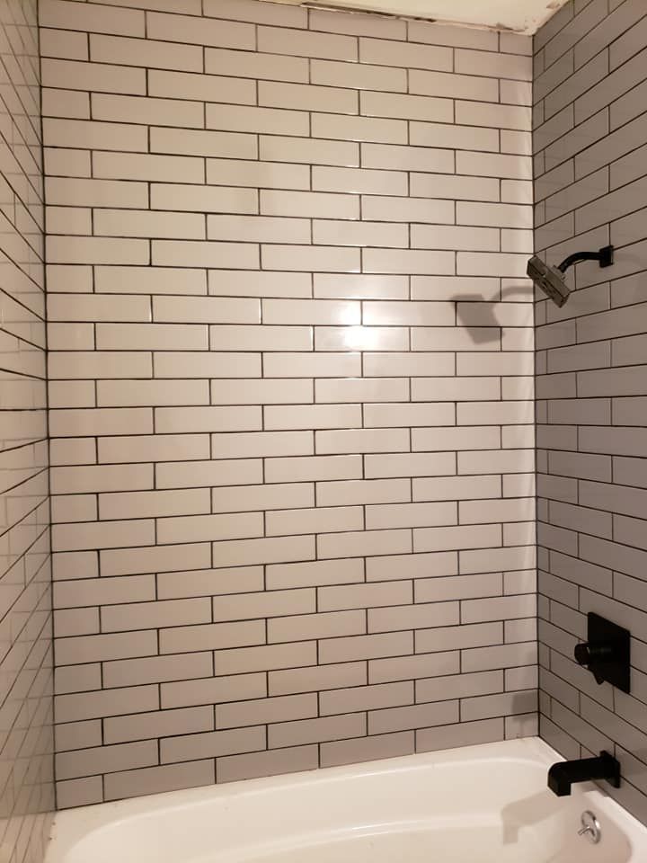 A bathroom with white brick walls and a bathtub