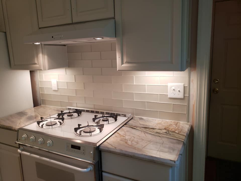A kitchen with a gas stove and a hood above it.