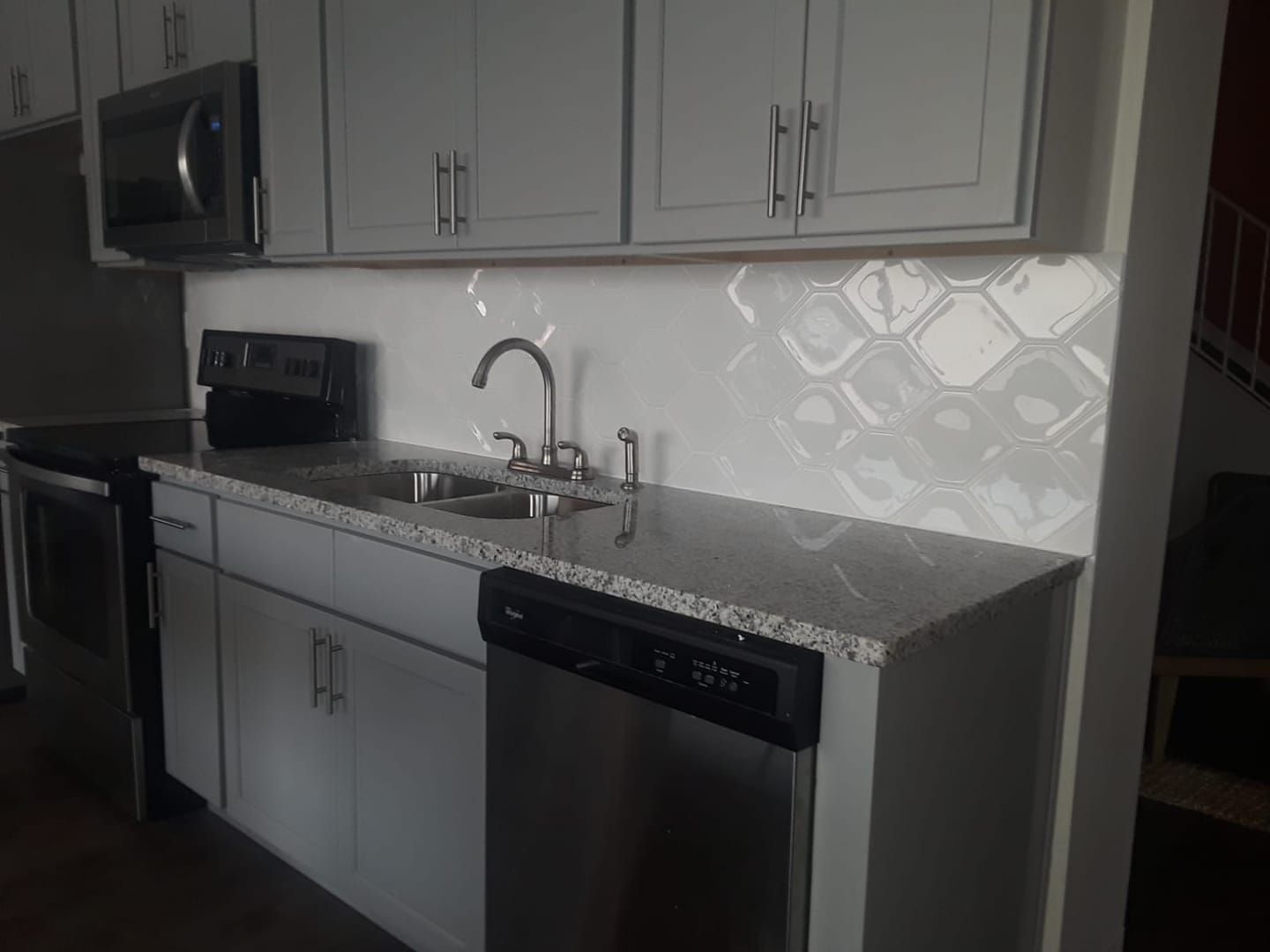 A kitchen with white cabinets , a sink , a microwave , and a dishwasher.