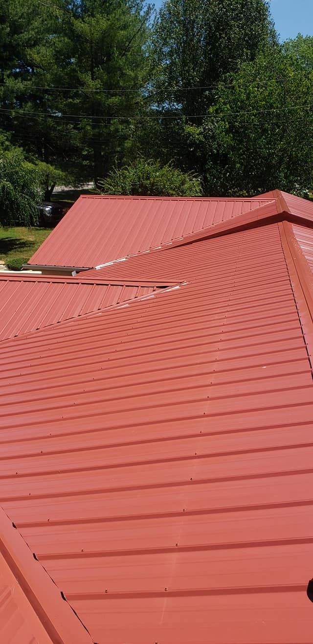 A close up of a red roof with trees in the background.