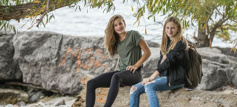 two girls sitting by the water 