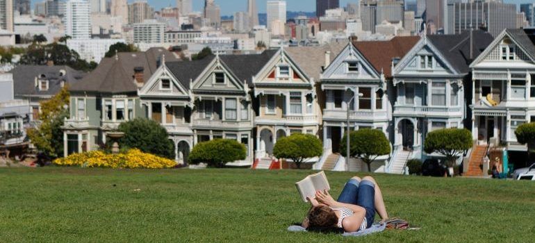 a woman lying on the grass and reading a book