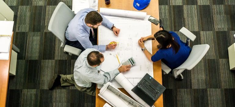 A group of people are sitting around a table looking at a blueprint.