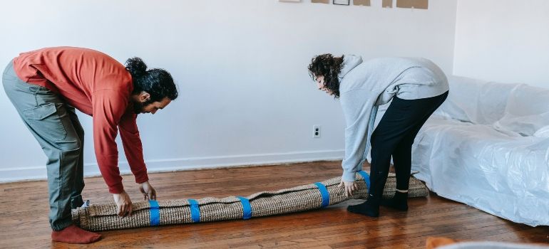 A couple moving a carpet 