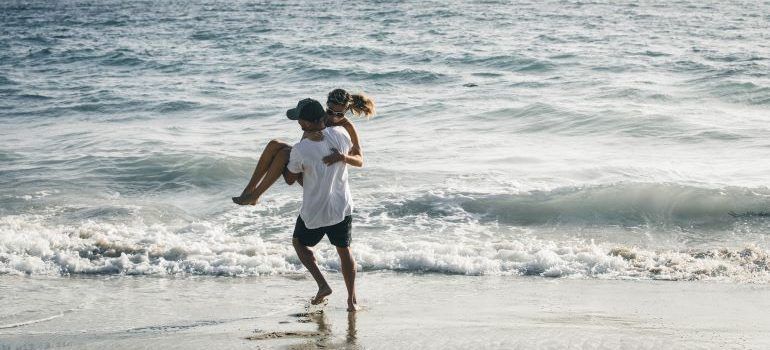 A man is carrying a woman on his shoulders on the beach.
