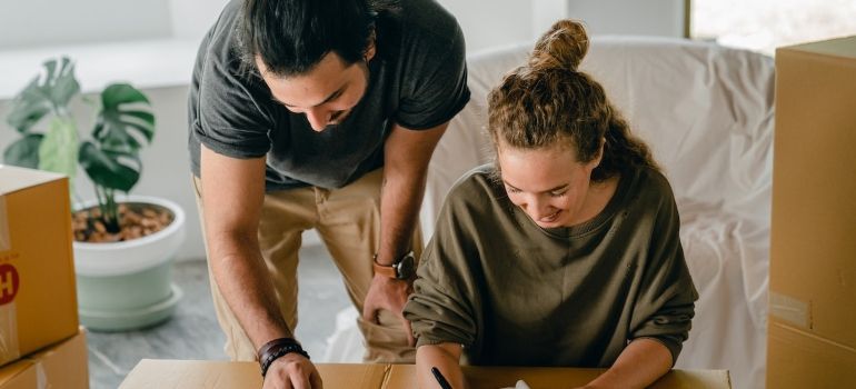 two people packing boxes and making an inventory