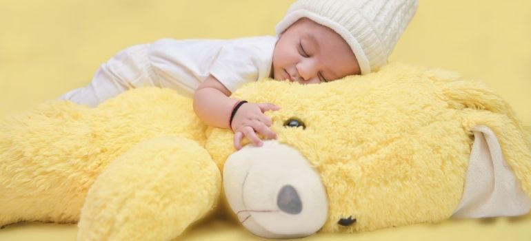 a newborn child sleeping on a yellow teddy bear to represent safe sleeping environment as you prepare your San Francisco home for a new baby