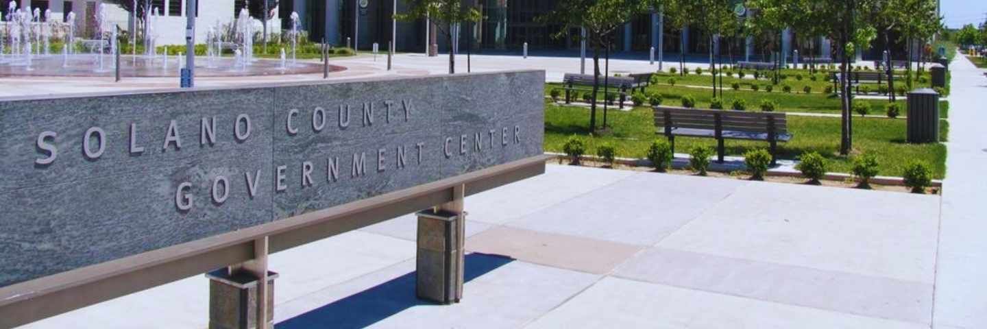 A sign for the gilroy library is in front of a parking lot.