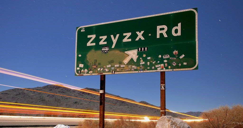 Exit to Zzyzx Road — one of the most unusually named roads in the U.S., located in the California desert. Green road sign for