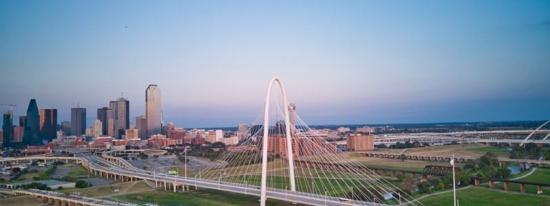 Downtown Dallas skyline with Margaret Hunt Hill Bridge at sunset, iconic Dallas Texas landmark view.