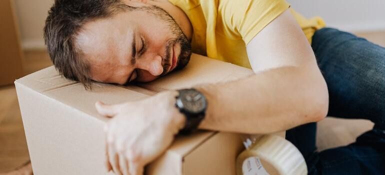 A man is sleeping on top of a cardboard box.