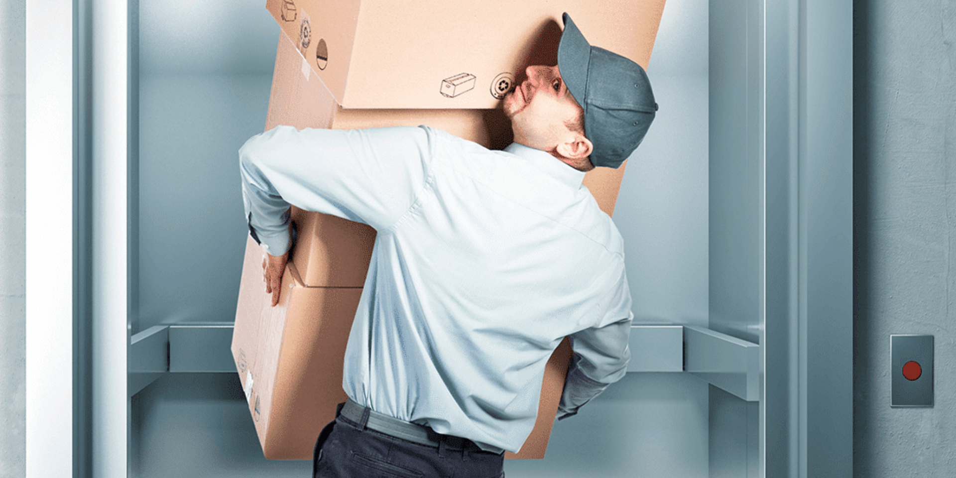 Man carrying boxes into an elevator apartment building.