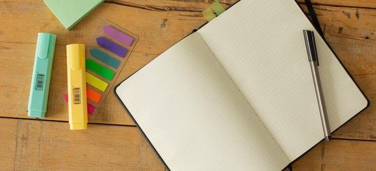 An open notebook with a pen and sticky notes on a wooden table.