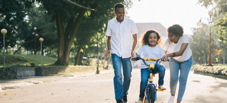 parents teaching their daughter to ride a bicycle