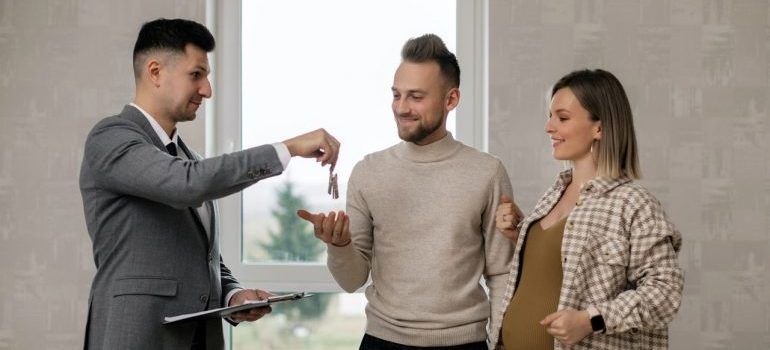Real estate agent handing a keys to a young couple