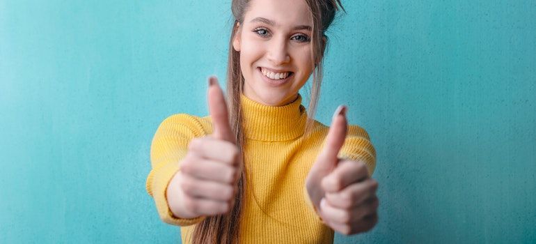 a woman in yellow showing thumbs up