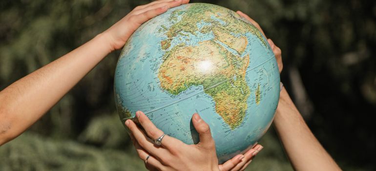 Hands holding a globe in as a symbol for environmentally conscious packing and unpacking tips