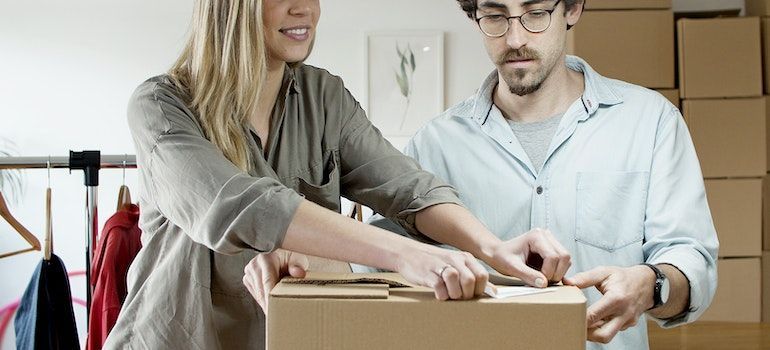 Men and woman sealing a box.