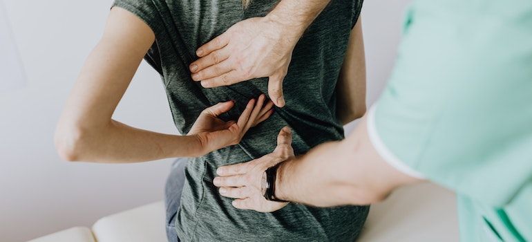 person getting their back checked by a doctor