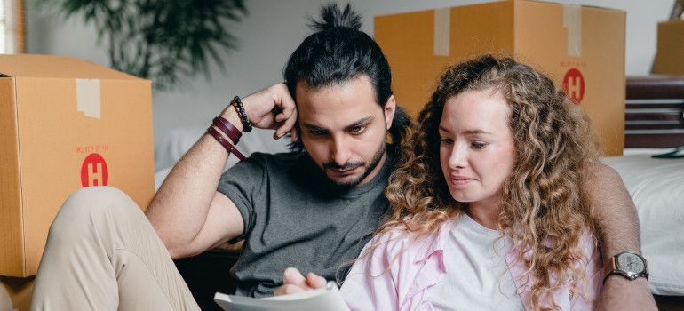 A young couple making a moving checklist to avoid tasks people forget about after moving to a new city
