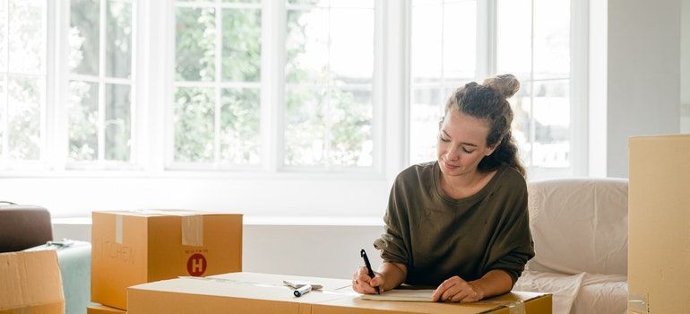 A woman writing a list on a moving box