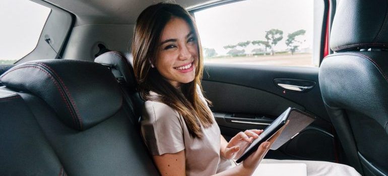 woman in a car smiling, holding documents