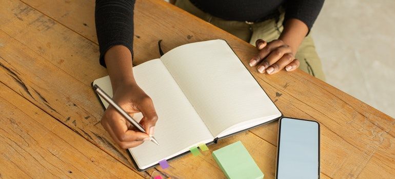 a woman writing in the notebook