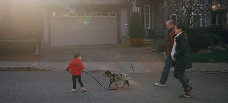 family with a kid walking a dog