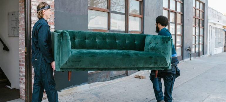 Two men moving a green couch