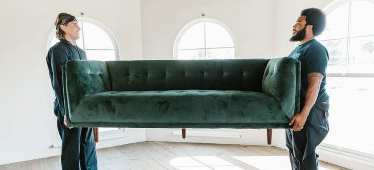 Two men carrying a green sofa.