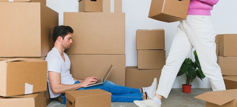 man with laptop surrounded by boxes