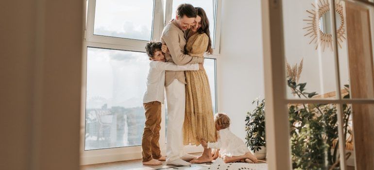 Family of four hugging in a new home after surpassing psychological effects of moving frequently on adults and kids