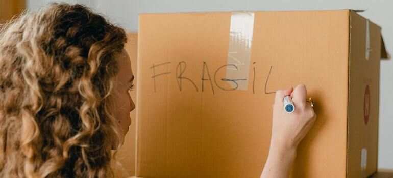 A woman labeling a box as fragile