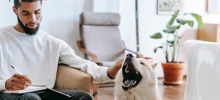 A man petting a dog while writing notes